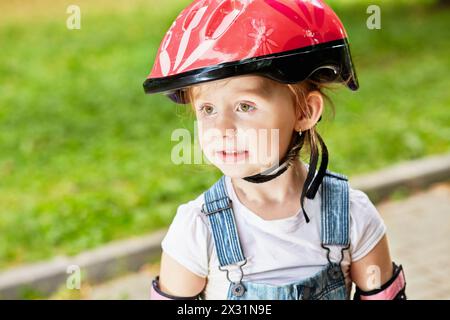 Gros plan portrait de la petite fille dans le casque de protection rouge Banque D'Images