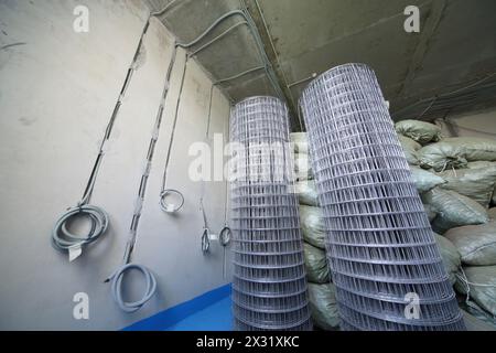 Rouleaux de caillebotis métalliques et sacs de matériaux de construction dans la pièce en travaux de réparation Banque D'Images