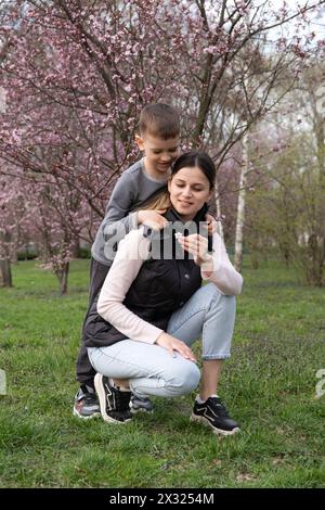 Fils donne à sa mère une petite fleur de cerisier en fleur au printemps Banque D'Images