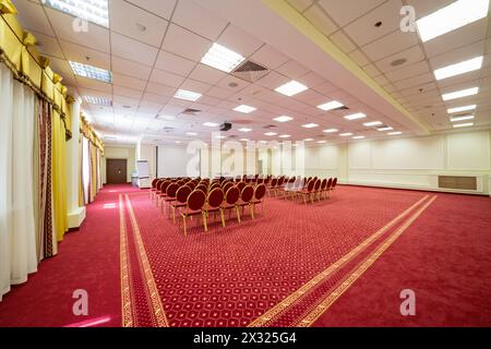 Écran et chaises dans une élégante salle de conférence vide avec un tapis rouge sur le sol Banque D'Images