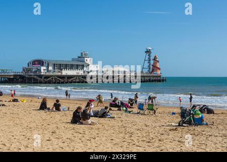 West Cliff Beach, Bournemouth, Royaume-Uni - 30 mars 2024 : les gens se détendent sur la plage avec la jetée de Bournemouth en arrière-plan. Banque D'Images