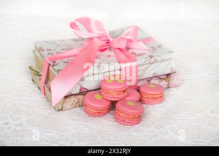 Biscuits à la rose avec de la crème sur la table avec des livres enveloppés ruban Banque D'Images