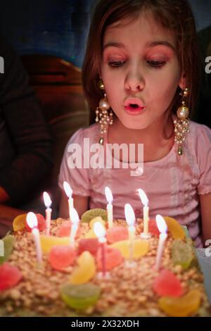 La petite fille souffle des bougies sur le gâteau d'anniversaire Banque D'Images