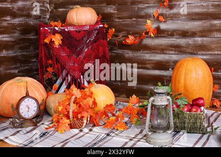 Orange grosses citrouilles, vieille lampe, horloge et panier de fruits sur tapis dans la chambre avec intérieur d'automne. Banque D'Images