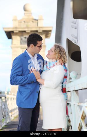 Heureuse femme enceinte en robe blanche et l'homme embrasser sur le pont. Banque D'Images