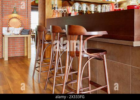 Trois grands tabourets en bois au comptoir avec boissons et verres dans le café Banque D'Images