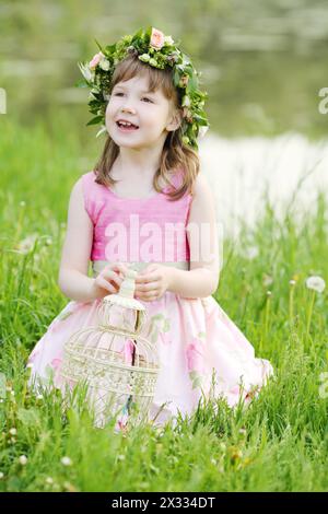 Petite jolie fille s'assoit avec le coop blanc sur l'herbe verte dans le parc d'été. Banque D'Images