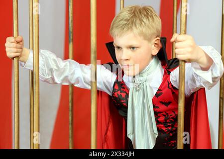 Garçon en manteau rouge se libère de la cage dorée Banque D'Images