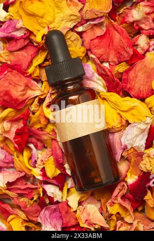 Une bouteille brune avec un compte-gouttes sur un tas de pétales de fleurs de couleur sèche fond Banque D'Images