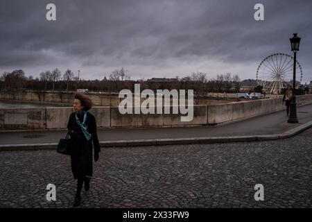 Une femme âgée vêtue de riches et luxueux vêtements traditionnels se promène le long du Pont Royal avec la grande roue dans le jardin des Tuileries à Paris Banque D'Images