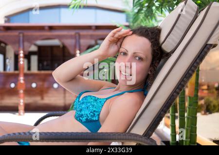 Femme allongée dans une chaise longue sur le fond de la barre en bois Banque D'Images