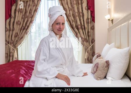 femme en peignoir avec une serviette sur la tête dans une chambre d'hôtel Banque D'Images