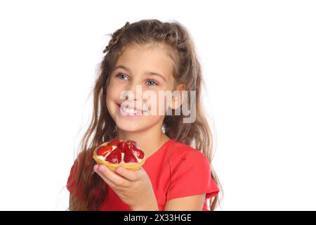 Portrait d'une petite fille dans une robe rouge tenant un gâteau aux fraises isolé sur blanc Banque D'Images