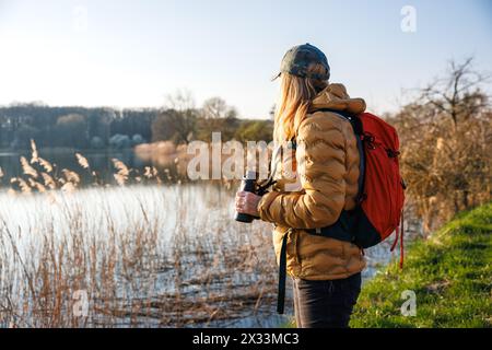 Une femme biologiste observe les oiseaux avec des jumelles. Observation des oiseaux et observation des animaux sauvages au lac. Biologie dans la nature Banque D'Images
