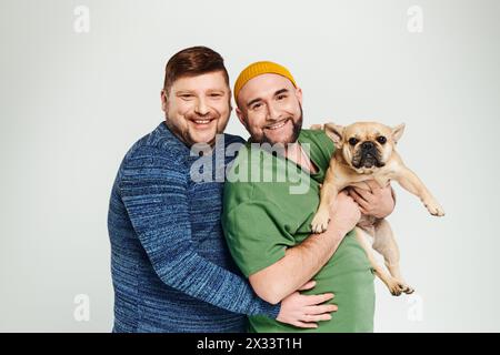 Deux hommes tiennent doucement un petit chien dans ses bras. Banque D'Images