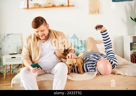 Deux hommes sont assis sur un lit, pris dans leur téléphone portable. Banque D'Images