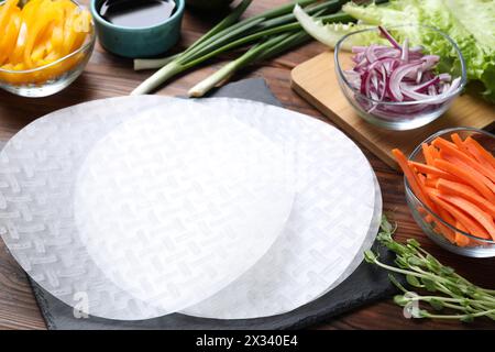 Papier de riz, microgreens et autres ingrédients pour les rouleaux de printemps sur la table en bois, gros plan Banque D'Images