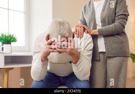 Femme âgée essayant de faire la paix avec son mari âgé bouleversé après la querelle assise à la maison. Banque D'Images