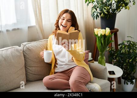 Femme d'âge moyen engrossée dans un livre alors qu'elle était assise sur un canapé confortable. Banque D'Images