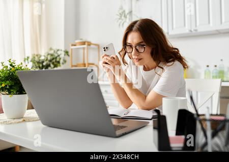 Femme d'âge moyen assise à table, engrossée dans le travail d'ordinateur portable. Banque D'Images