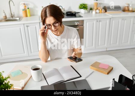 Une femme d'âge moyen s'engouffrant dans un carnet et vérifiant son téléphone portable alors qu'elle était assise à une table. Banque D'Images