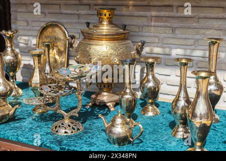 Des vases de luxe et d'autres plats en laiton avec des motifs en relief se tiennent sur le comptoir d'un bazar de rue à Boukhara Banque D'Images