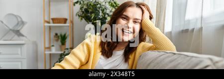 Femme d'âge moyen dans la pensée profonde, la main sur la tête, assise sur le canapé. Banque D'Images