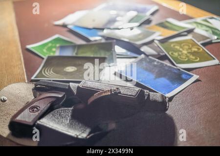 pistolet en plastique dans un étui en cuir avec des cartes émiettées sur la table Banque D'Images