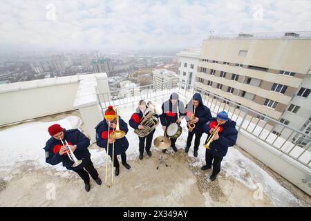 Brass band de six musiciens jouent sur le toit d'un grand bâtiment en hiver, vue de dessus Banque D'Images