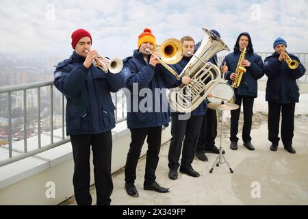 Brass band de six musiciens jouent sur le toit d'un grand bâtiment le jour d'hiver Banque D'Images