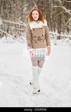 Adolescente avec des accolades sur les dents se tient sur des patins sur la voie de glace dans le parc. Banque D'Images