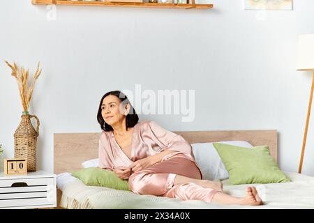 Une femme mature dans des vêtements confortables se relaxant sur le dessus d'un lit dans une pièce sereine. Banque D'Images