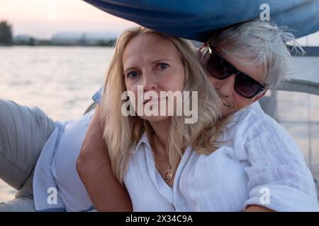 Couple mature dans une étreinte sereine, un moment de connexion sur l'eau, avec le calme du crépuscule reflété dans leurs expressions de contenu. Haute qualité Banque D'Images