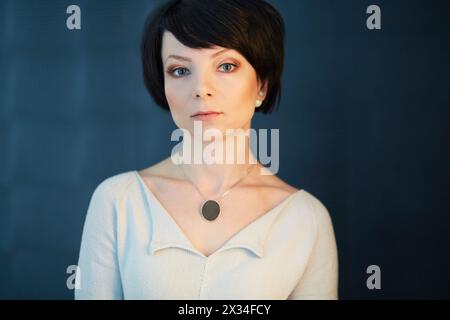 Portrait d'épaule d'une femme aux cheveux foncés en robe tricotée blanche. Banque D'Images