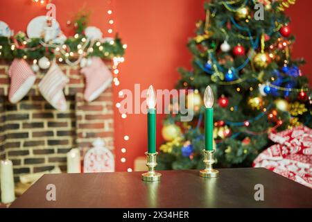 Intérieur de la chambre avec firtree décoré pour les vacances de noël, cheminée, murs rouges. Concentrez-vous sur les bougies électriques à table. Banque D'Images