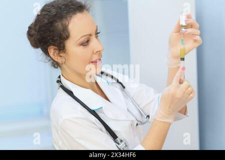 Le travailleur de la santé recueille le médicament dans la seringue à partir du flacon, debout dans la salle d'examen Banque D'Images