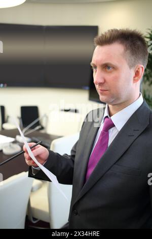 Homme d'affaires tenant un morceau de papier et un crayon dans le bureau Banque D'Images