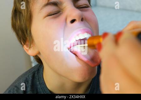 Jeune garçon ayant sa gorge examinée par un professionnel de la santé, concentrez-vous sur la gorge Banque D'Images