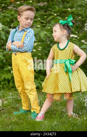 Petit garçon et fille se tiennent debout sur la pelouse herbeuse se regardant l'un l'autre. Banque D'Images