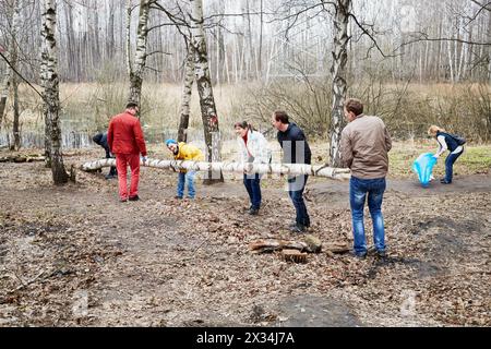 MOSCOU, RUSSIE - 18 avril 2015 : les gens portent un gros tronc d'arbre pendant les travaux de nettoyage au complexe résidentiel Elk Island. Plus de 2,5 millions de personnes font parti Banque D'Images