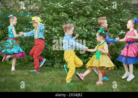 Trois couples d'enfants dansent sur la pelouse herbeuse en plein air. Banque D'Images