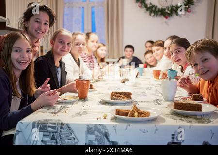 Groupe de treize enfants assis à table pendant la partie de thé. Banque D'Images