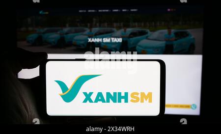 Personne tenant le téléphone portable avec le logo de la société de mobilité vietnamienne Xanh SM en face de la page Web de l'entreprise. Concentrez-vous sur l'affichage du téléphone. Banque D'Images