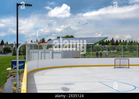 Calgary Alberta Canada, 05 juillet 2023 : patinoire de hockey extérieure pendant l'été avec des cerceaux de basket-ball et un plancher de ciment donnant sur un toit solaire pour un gazebo. Banque D'Images