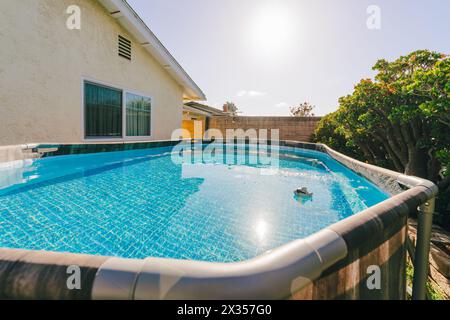 Piscine hors sol dans une cour arrière entourée de verdure. Banque D'Images