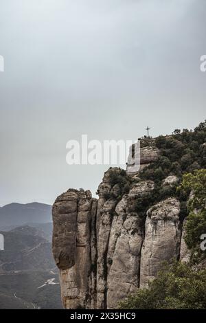 Une croix au sommet d'une montagne dans la chaîne de Montserrat, près de Barcelone, Catalogne, Espagne. Banque D'Images