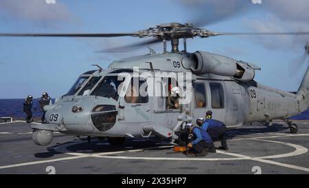 Les marins utilisent des cales et des chaînes pour fixer un SH-60S SeaHawk attaché au Helicopter Sea combat Squadron (HSC) 25 au pont d'envol du navire amphibie de débarquement USS Harpers Ferry (LSD 49) alors que le navire transite par l'océan Pacifique, le 13 avril 2024. Harpers Ferry et les éléments embarqués de la 15th MEU mènent des opérations de routine dans la zone d'opérations de la 7th Fleet des États-Unis. La 7e flotte américaine est la plus grande flotte numérotée déployée vers l’avant de l’US Navy. Elle interagit et opère régulièrement avec des alliés et des partenaires pour préserver une région indo-pacifique libre et ouverte. (Photo de l'US Navy par Mass Communicati Banque D'Images