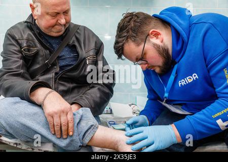 20 avril 2024, Donetsk, Ukraine : un médecin traumatologue de la Mission volontaire Frida est vu effectuer des procédures médicales sur la jambe blessée d'un homme âgé FRIDA Ukraine est une mission ukraino-israélienne de volontaires médicaux visant à aider la population civile. Des médecins bénévoles fournissent aux Ukrainiens touchés par les hostilités des médicaments de haute qualité. Ils organisent également des voyages en première ligne des régions désoccupées pour aider les civils qui y vivent. Ce travail bénévole a commencé dans la région de Kiev, suivie par Chernihiv, Sumy, Kharkiv, Mykolaïv, Kherson, Donetsk et d'autres régions où les civils ont dif Banque D'Images