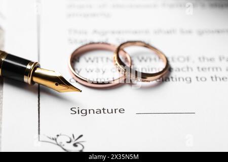 Contrat de mariage, stylo plume et anneaux de mariage sur table, gros plan Banque D'Images