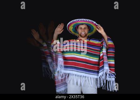 Photo stroboscopique d'un jeune mexicain en poncho avec chapeau sombrero sur fond sombre Banque D'Images